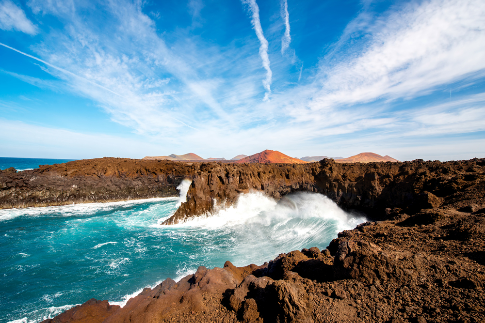 Los,Hervideros,Rocky,Coast,With,Wavy,Ocean,And,Volcanos,On